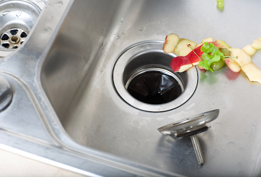 Food scraps on the edge of kitchen sink drain.