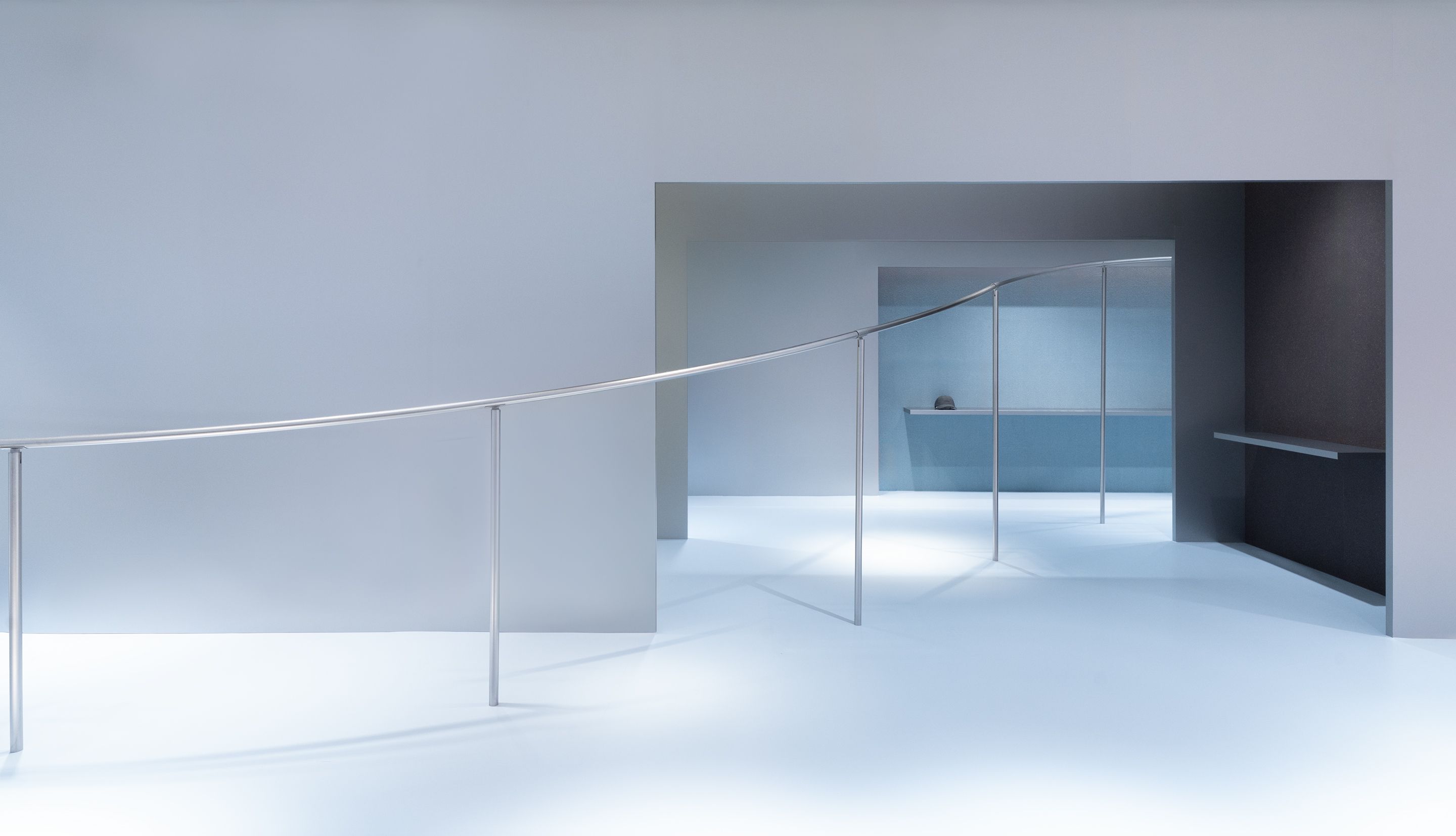 Minimalist gray interior with a curved metal railing and open doorways.