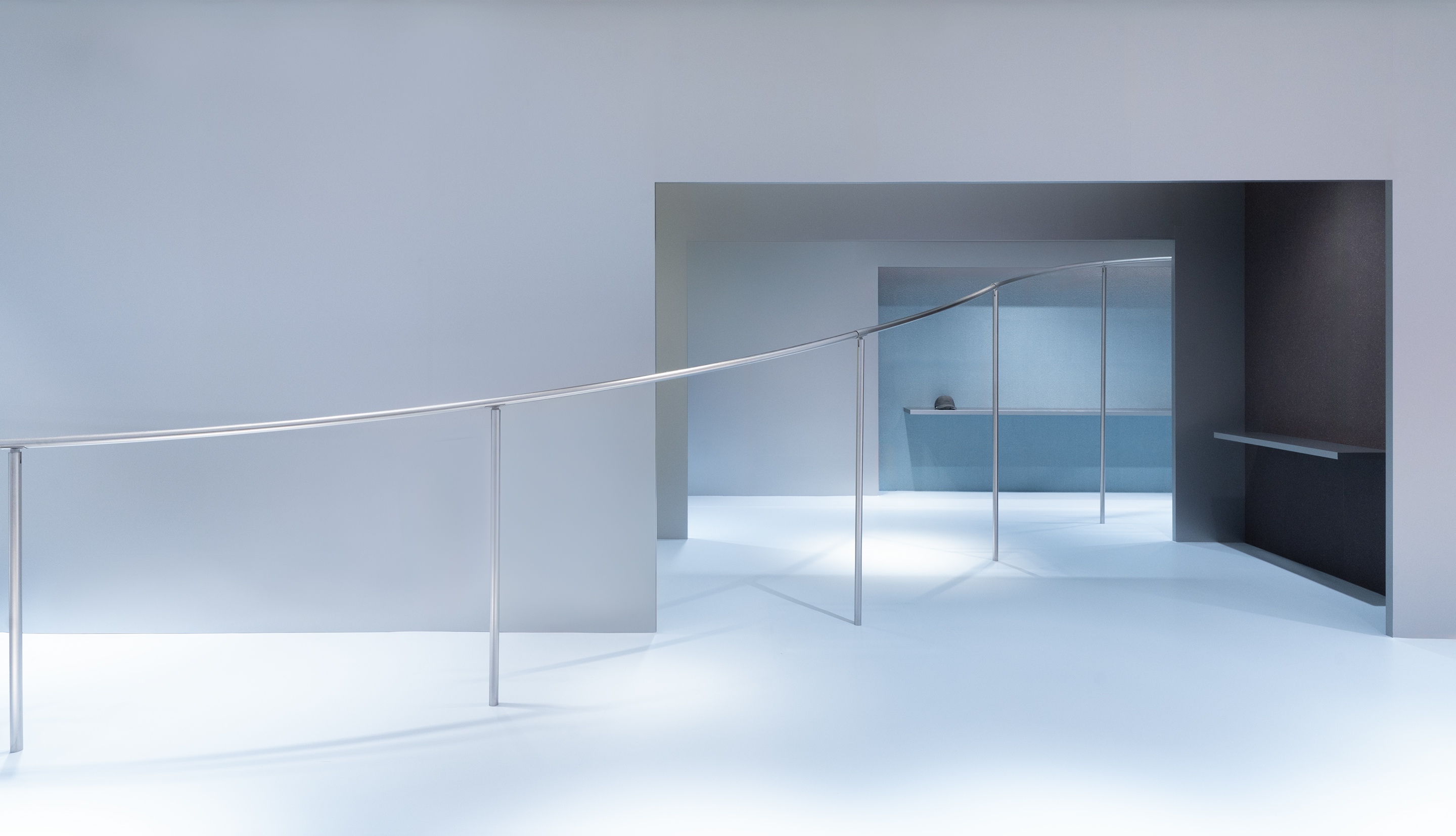 Minimalist gray interior with a curved metal railing and open doorways.