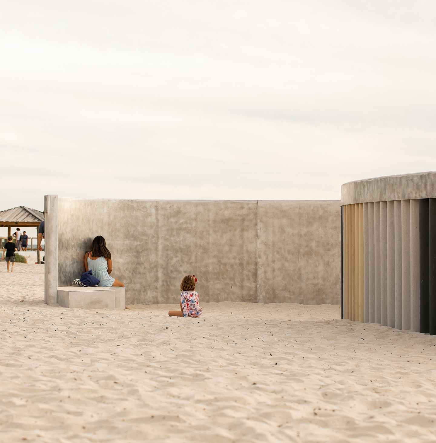 a woman and a child are sitting on a bench on the beach .