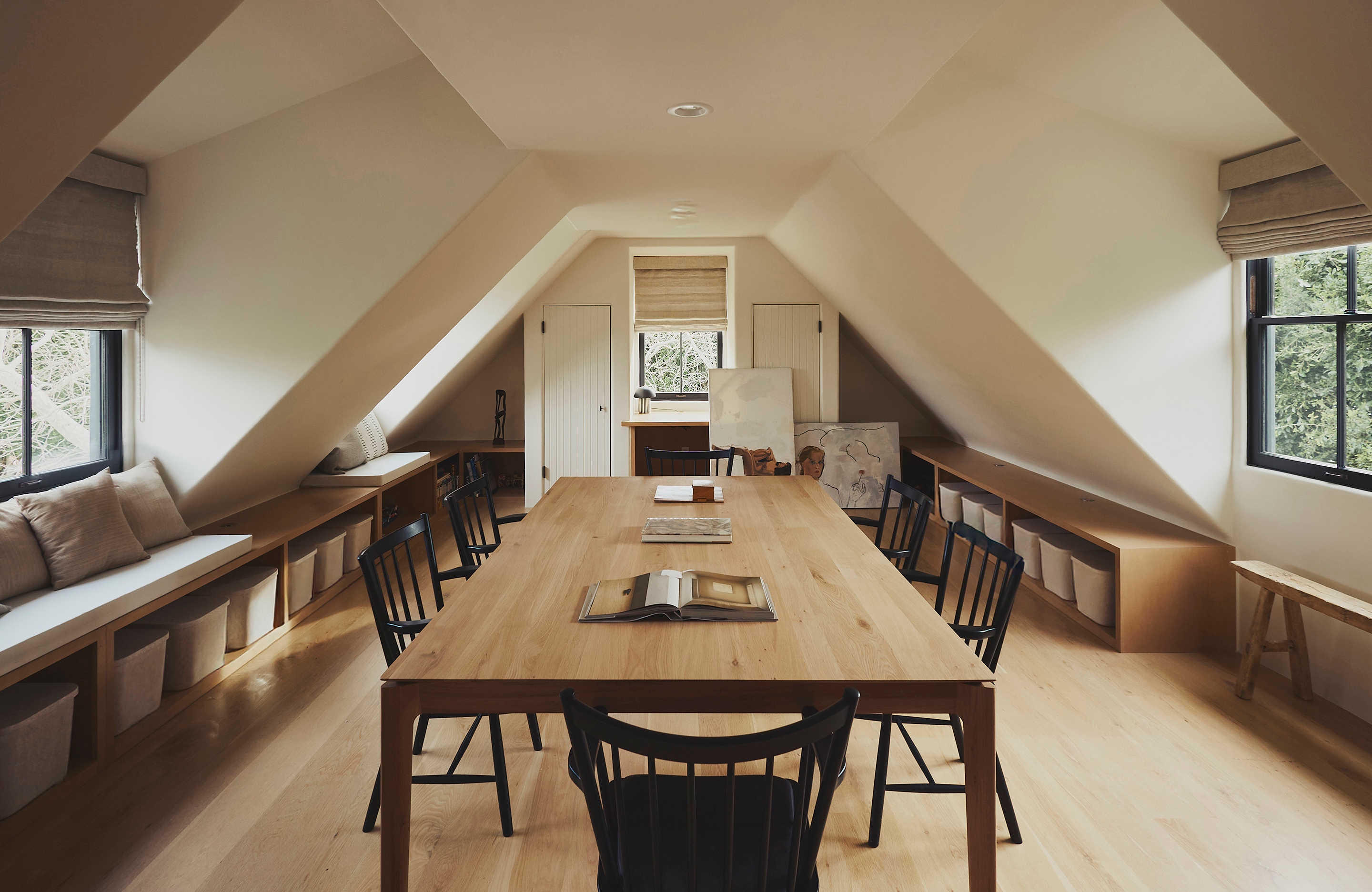 there is a large wooden table and chairs in the attic .
