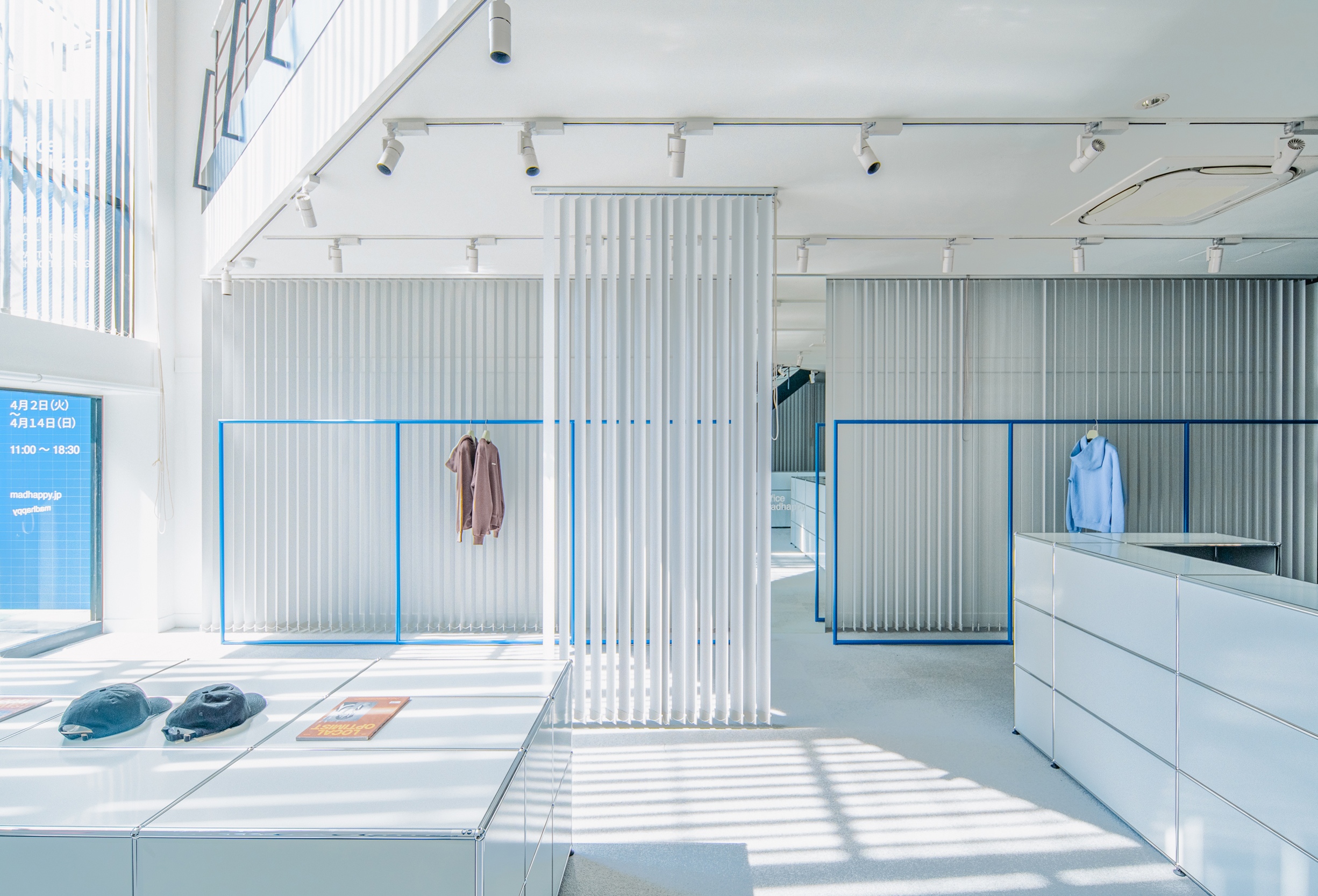 the interior of a clothing store with white walls and blue clothes racks .
