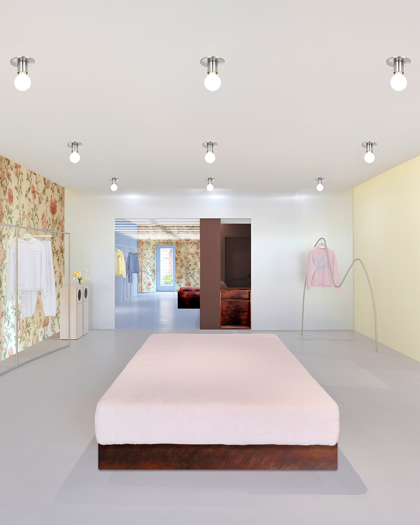 A minimalist room featuring a large pink platform bed, floral wallpaper, clothing racks, and an open doorway to another room.