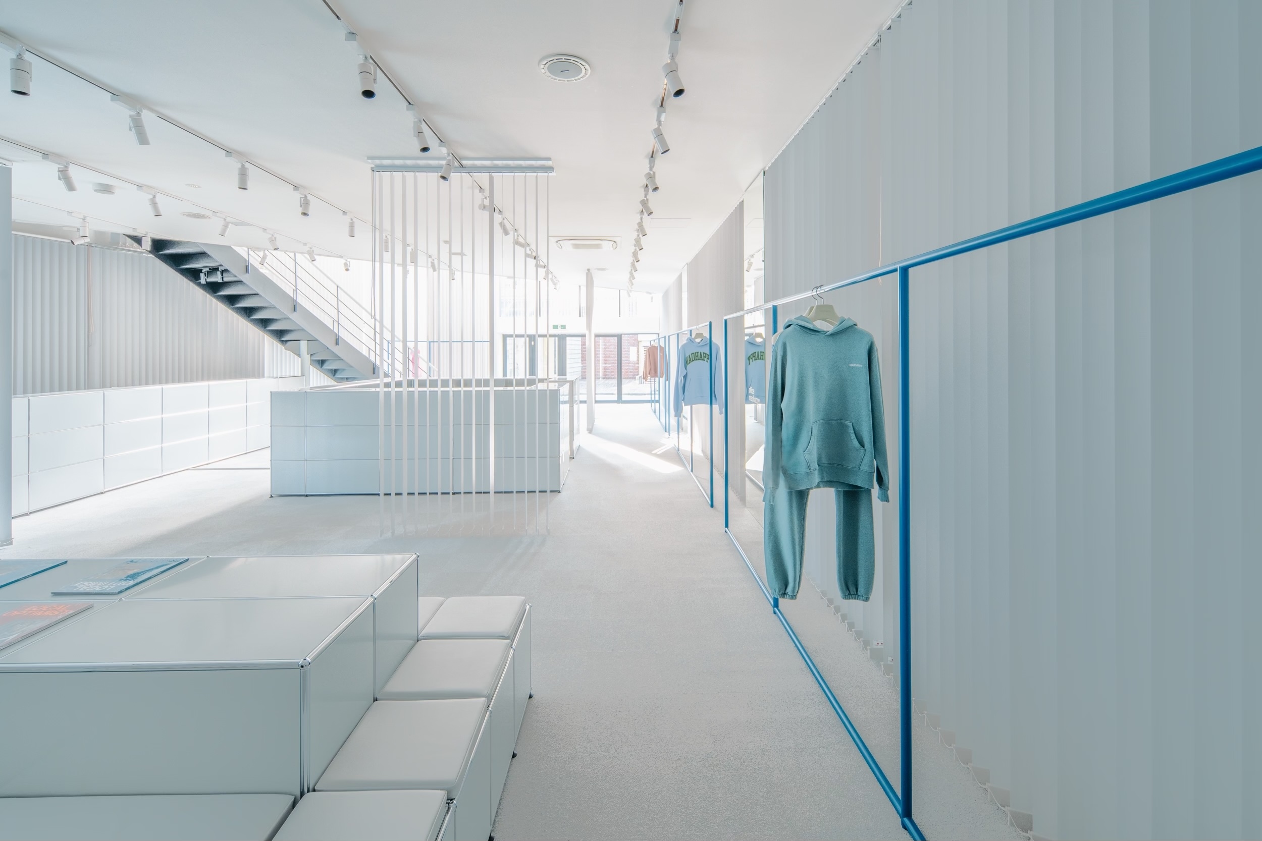 a store with clothes hanging on racks and a staircase .