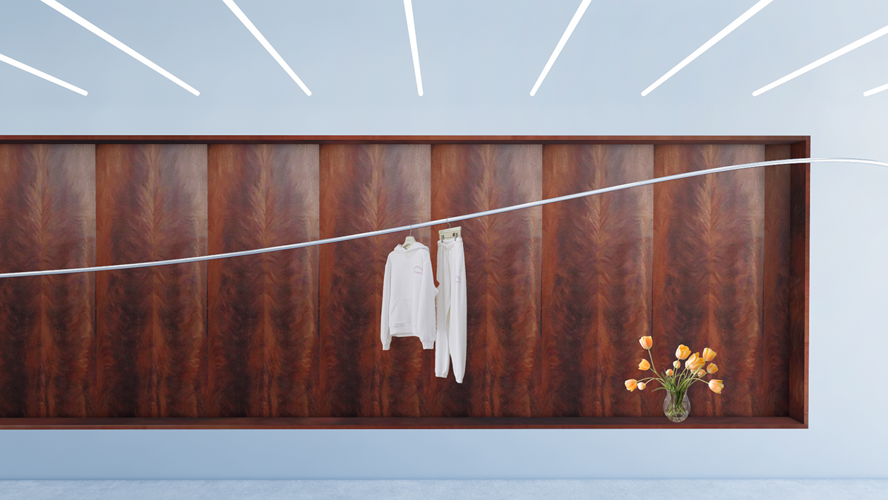 A white sweatshirt and sweatpants hanging on a rope above a dark wood panel with a vase of yellow flowers, under linear ceiling lights.