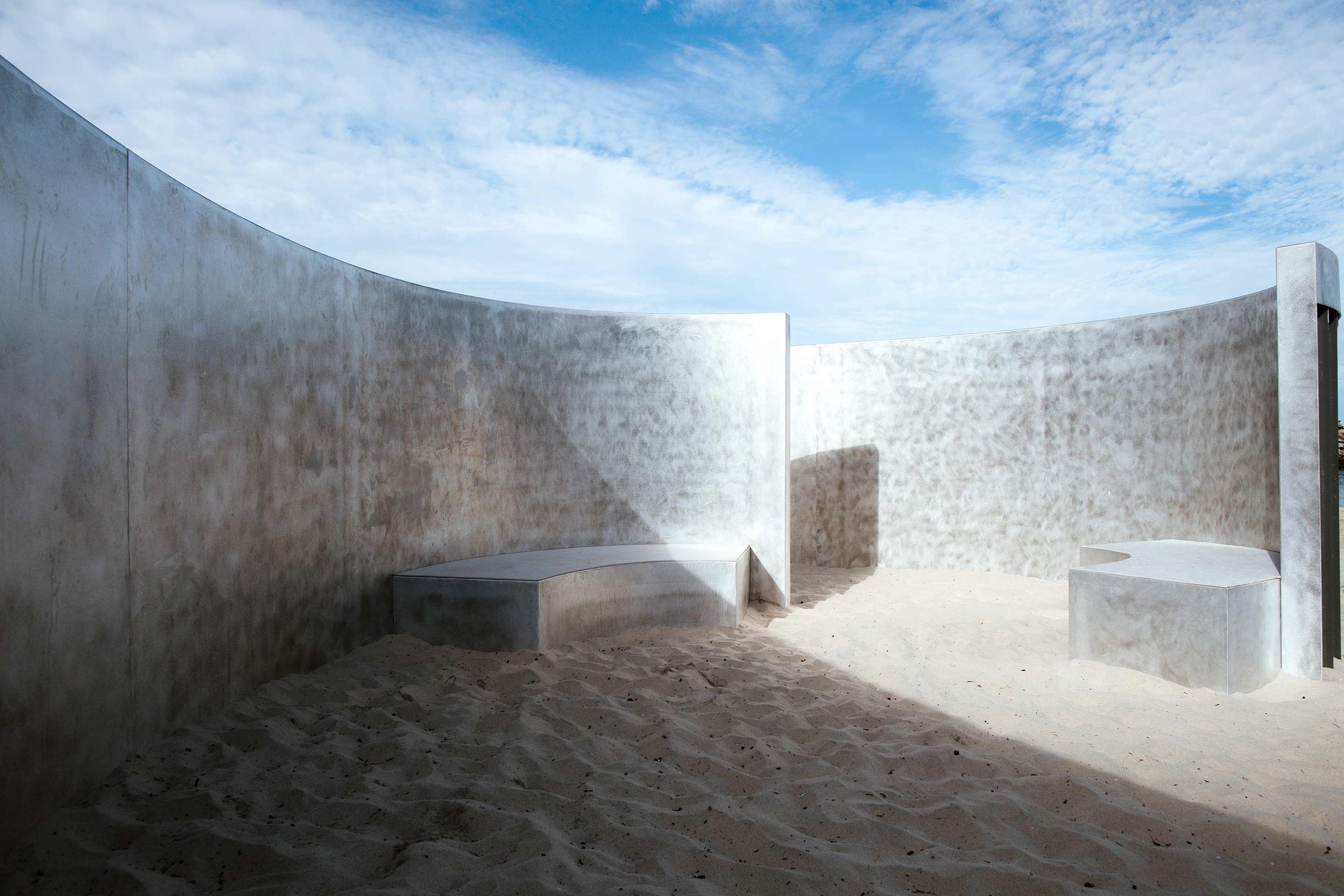 there is a concrete wall in the middle of a sandy area .