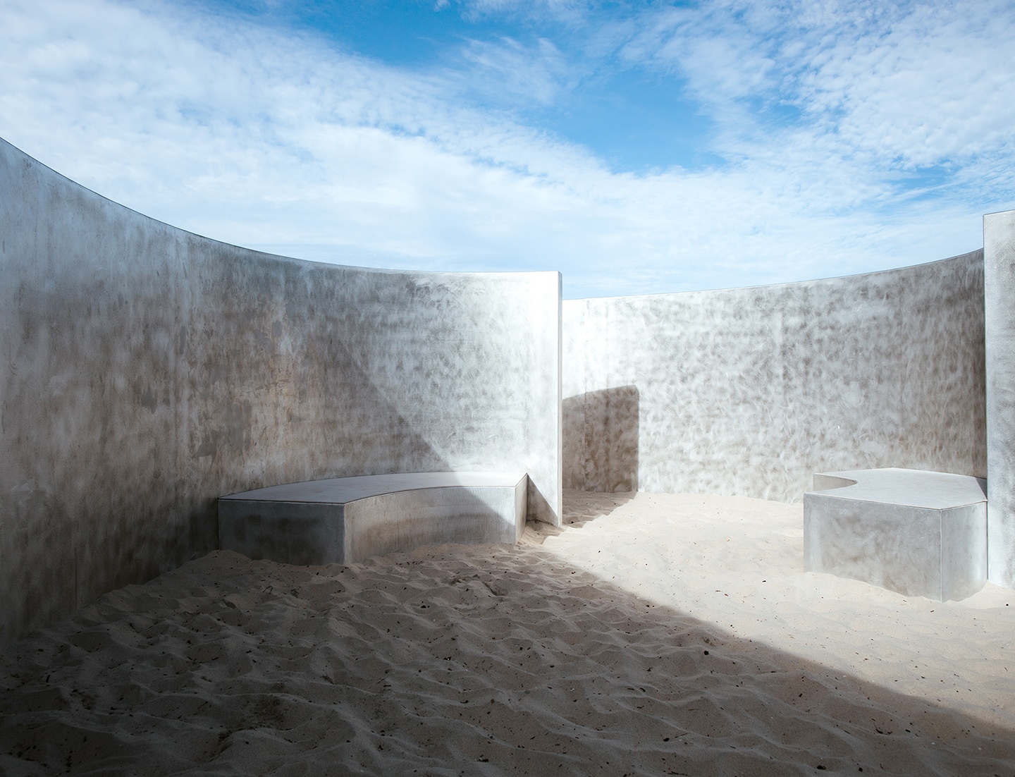 a room with a concrete wall and a bench in the middle of it .