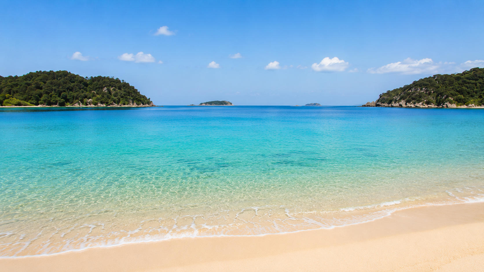 Clear turquoise water and a golden sand beach between two bush-covered headlands