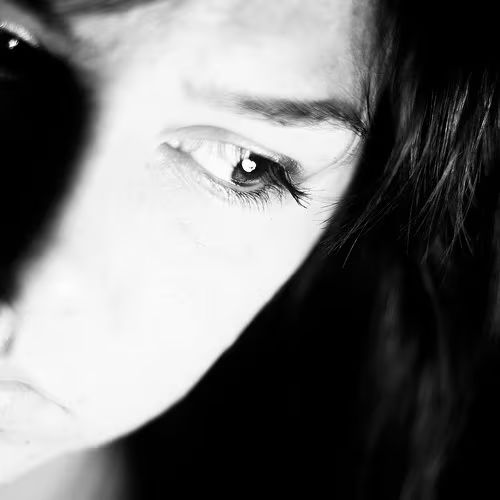 Close-up of a woman's face, half in shadow, looking worried