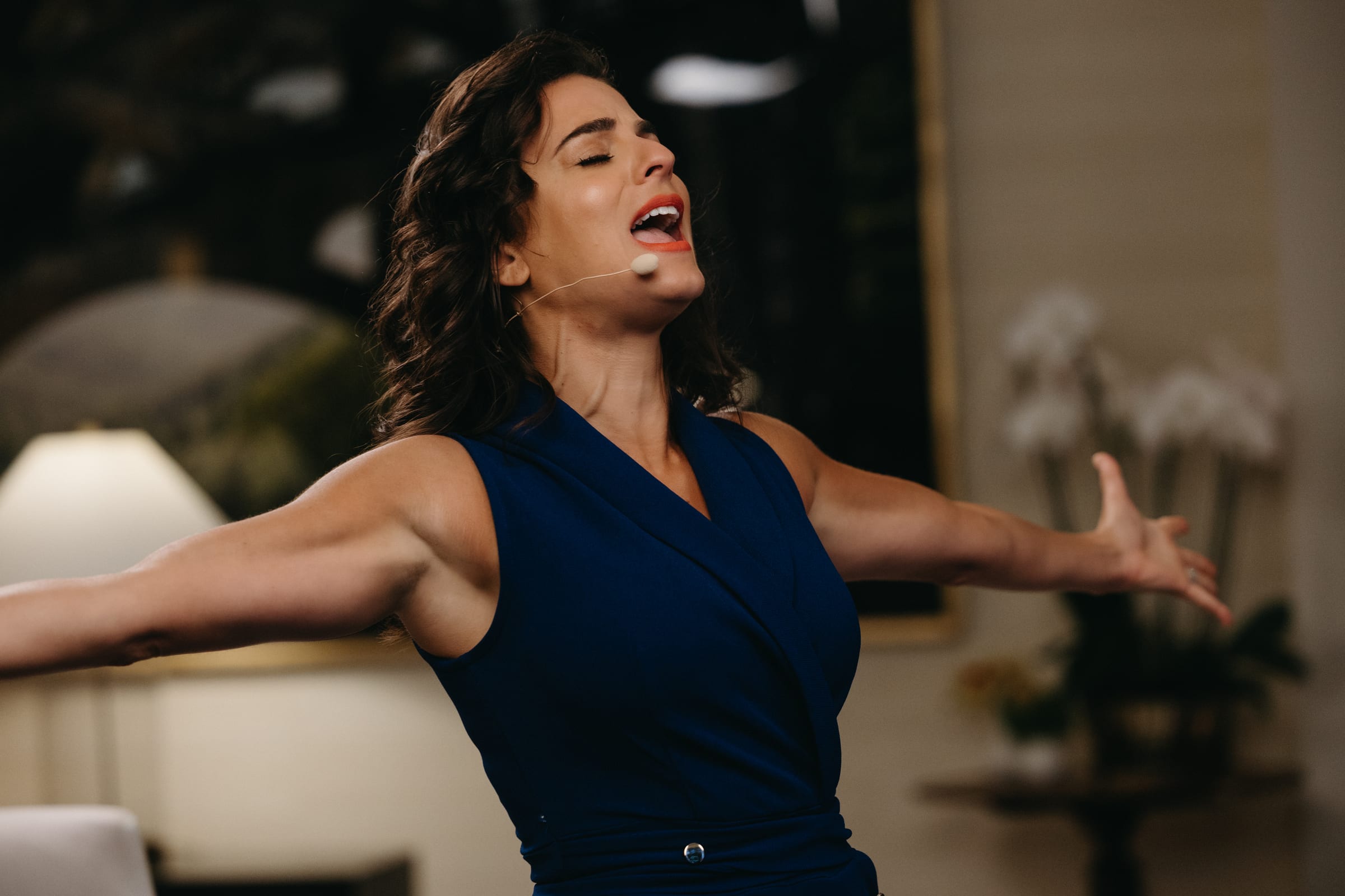 Renée Marino speaking with her arms open to an audience