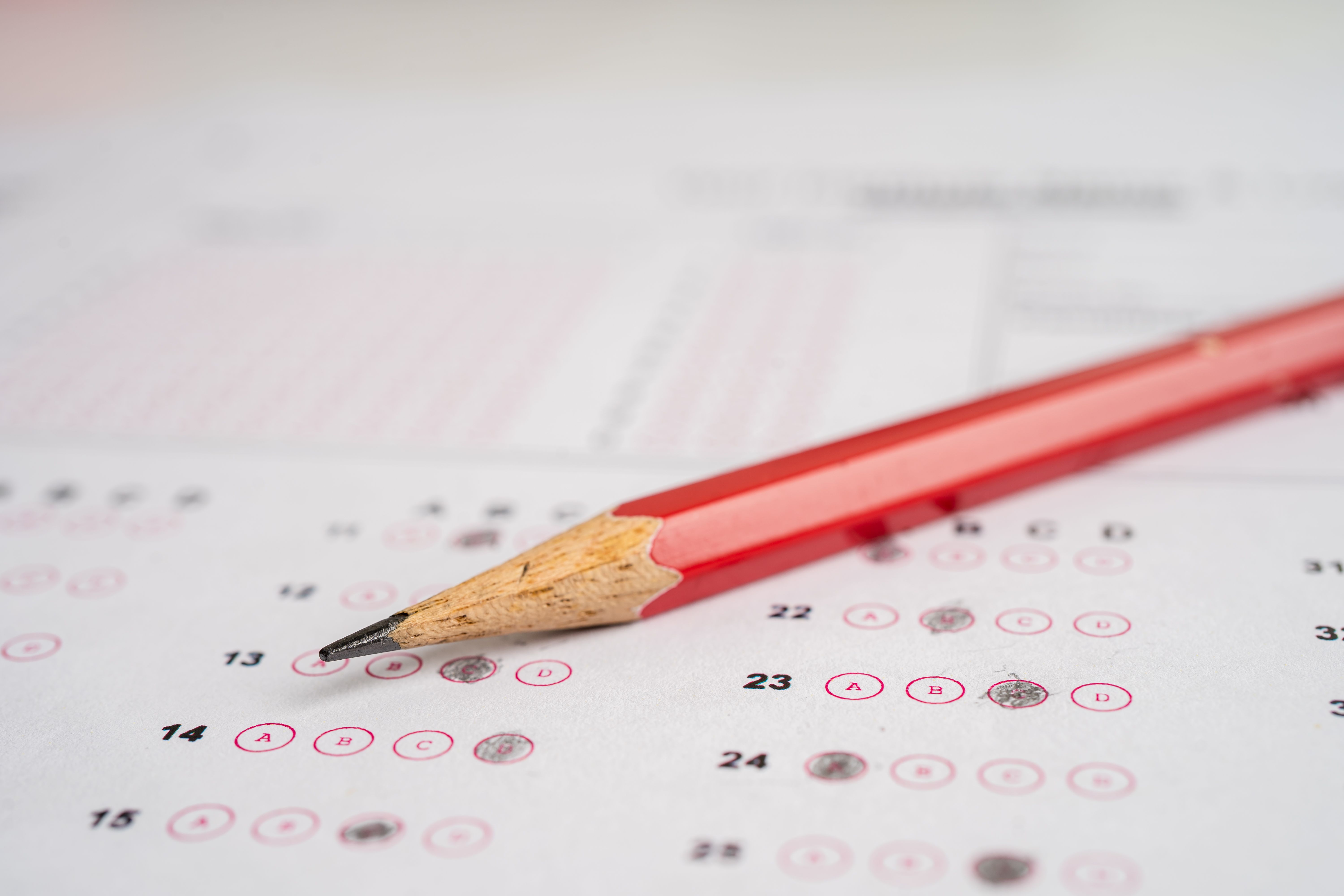 A red pencil resting on a multiple choice answer sheet with bubbles, representing preparation for the U.S. citizenship civics test