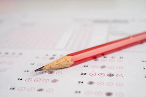 A red pencil resting on a multiple choice answer sheet with bubbles, representing preparation for the U.S. citizenship civics test