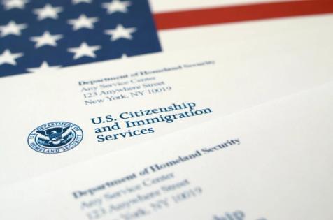 USCIS Backlog 2025 Immigration Case Documents American Flag | Immiva Close-up of USCIS (U.S. Citizenship and Immigration Services) paperwork beneath an American flag, illustrating the 2025 immigration backlog and Immiva’s guidance on keeping your case from stalling.