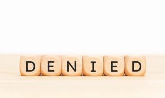 Wooden block letters spelling DENIED on a light wooden surface, representing H-4 EAD denial reasons and how to respond to USCIS refusals
