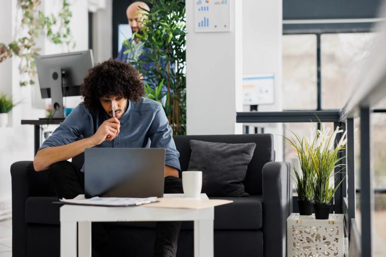 J-2 EAD holder working in the United States | Immiva Young professional working on a laptop in a modern US coworking space after receiving J-2 work authorization