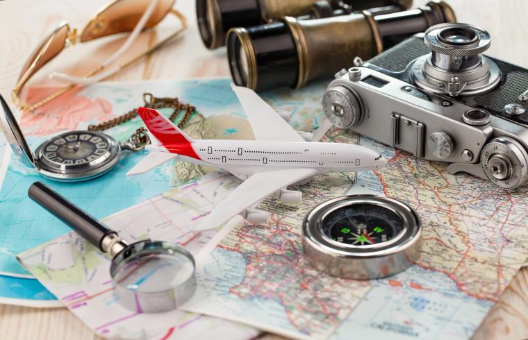 Travel Planning with Map Camera and Compass During I-751 Process | Immiva Flat lay of travel essentials including a world map, camera, compass, airplane model and binoculars, illustrating travel considerations while I-751 is pending