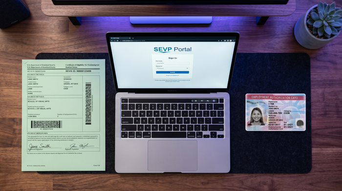 SEVP Portal Login on a Laptop With I-20 and EAD | Immiva Overhead desk shot of a laptop showing the SEVP Portal sign-in page beside an I-20 form and an EAD work permit card