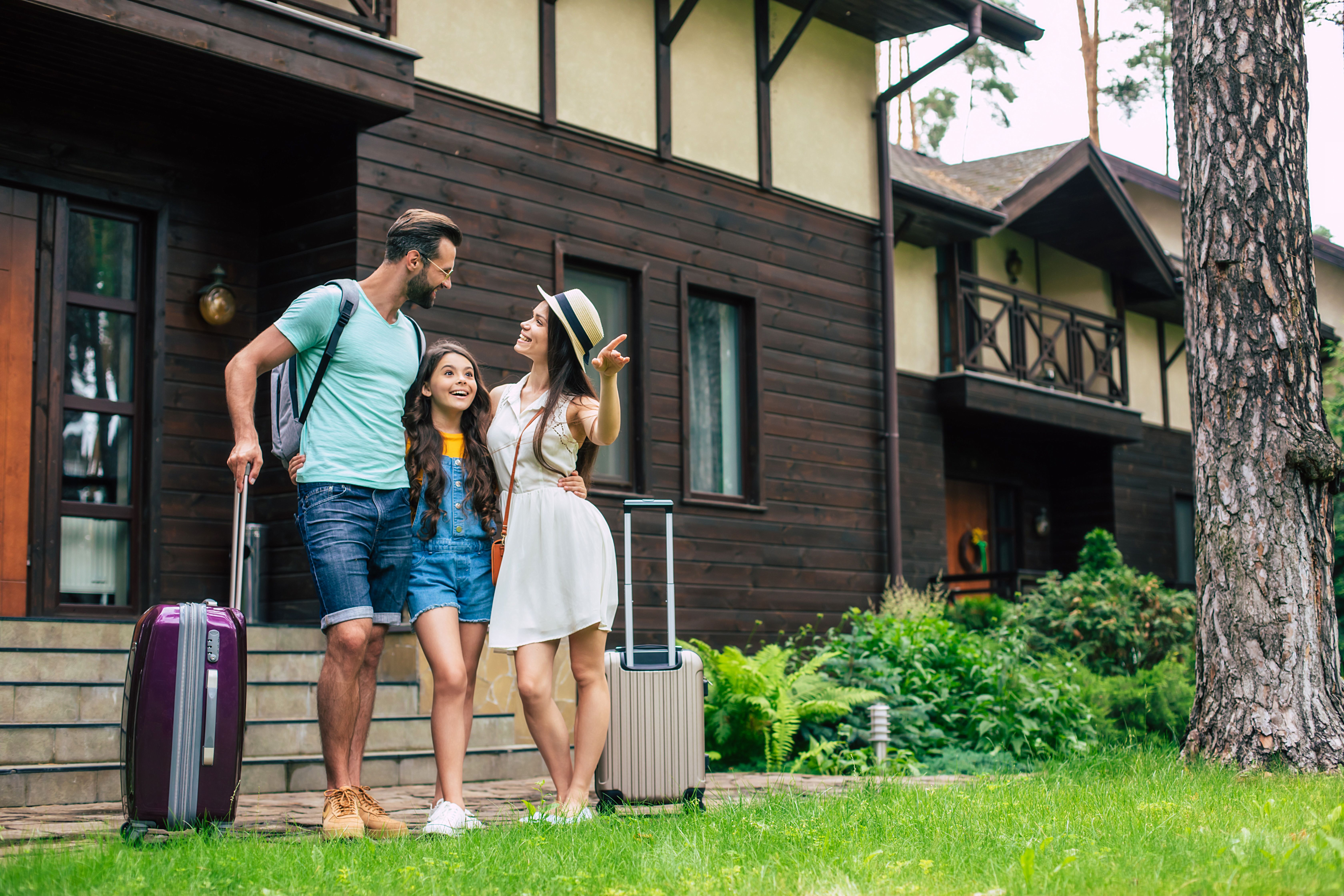 Family with suitcases standing outside their home, discussing N-400 physical presence and recent trips abroad before they apply for US citizenship – Immiva.
