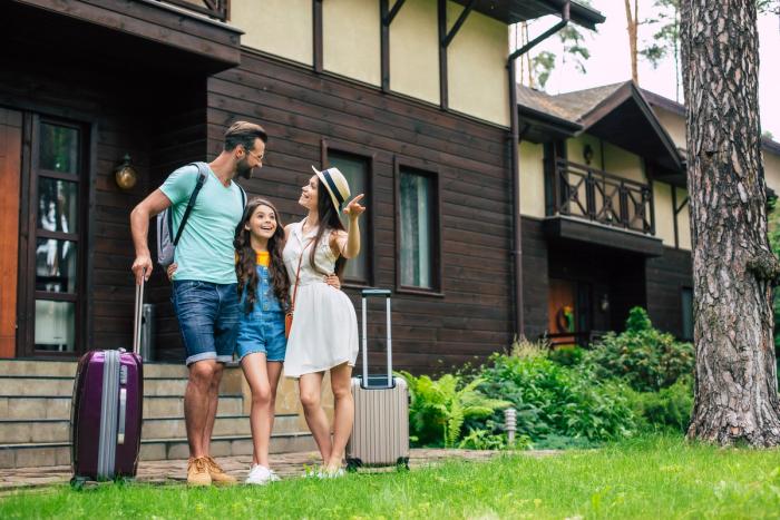 N-400 Travel Rules to Apply for US Citizenship | Immiva Family with suitcases standing outside their home, discussing N-400 physical presence and recent trips abroad before they apply for US citizenship – Immiva.
