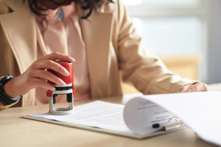 Close-up of a woman stamping official immigration documents, symbolizing the visa application process for H-4 dependents of H-1B workers