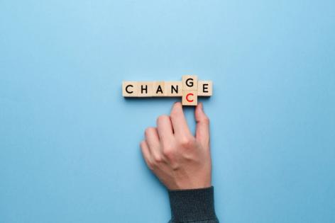 Hand rearranging wooden letter tiles spelling CHANGE to represent changing visa status to H4 using Form I-539 with Immiva help