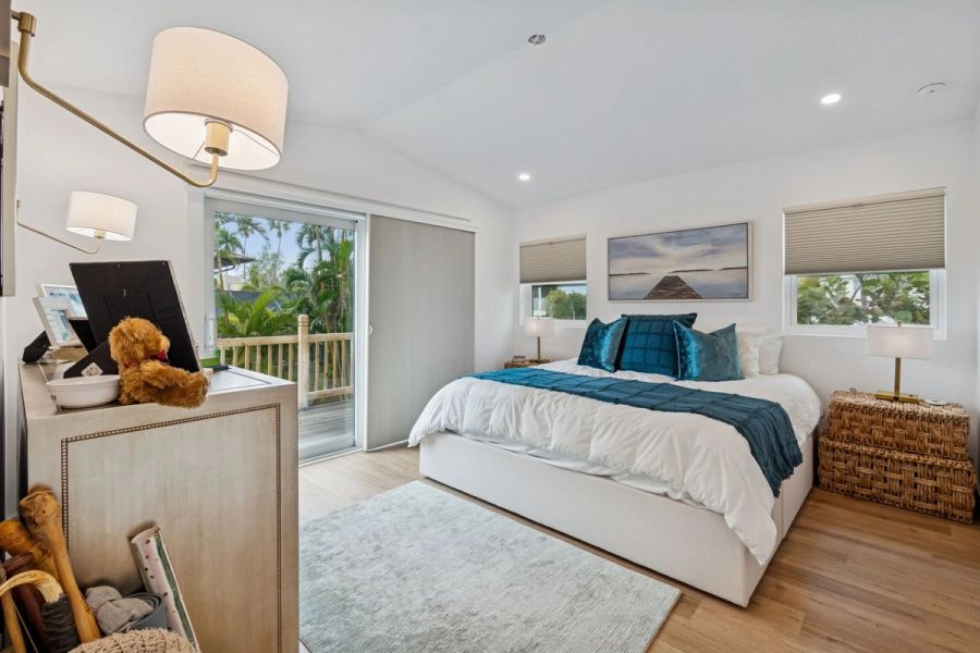 Interior primary bedroom king bed teal accents sliding glass door balcony — New home construction, Longboat Key