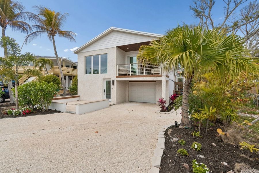 Coastal home exterior front view white stucco upper balcony tropical landscaping — New home construction, Longboat Key