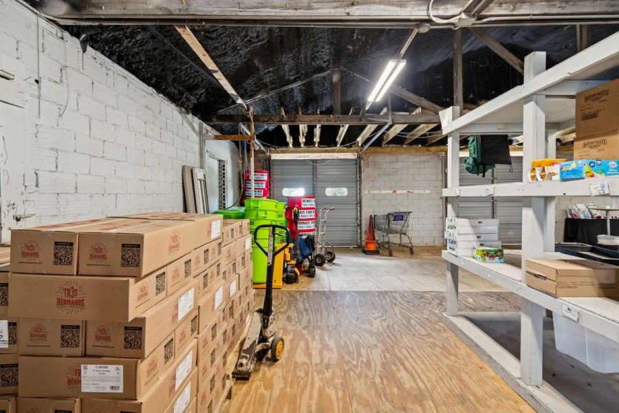 Interior commercial warehouse space stacked food boxes shelving pallet jack garage doors — Commercial building renovation, Palmetto
