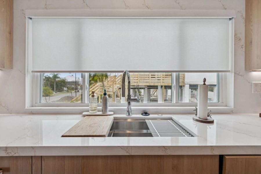 Interior kitchen sink closeup stainless undermount quartz countertop roller shade — New home construction, Longboat Key