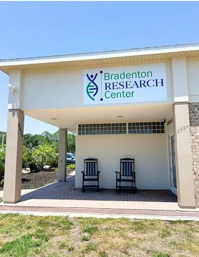 Covered front entrance with the Bradenton Research Center sign and two rocking chairs