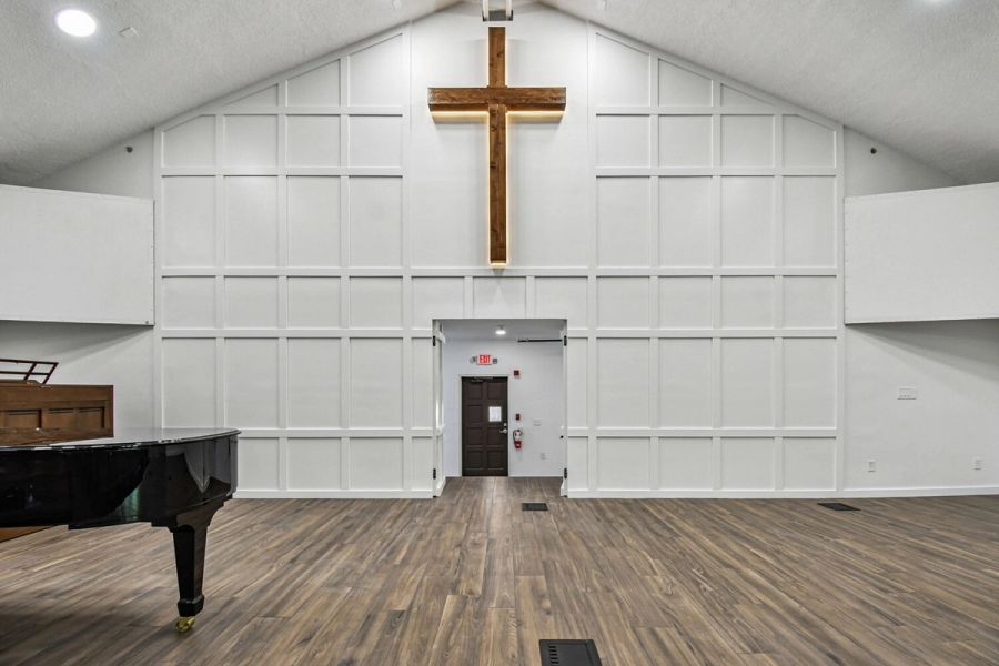 Interior view of stage entrance with wood flooring and illuminated cross — Roser Memorial Community Church, Anna Maria, FL