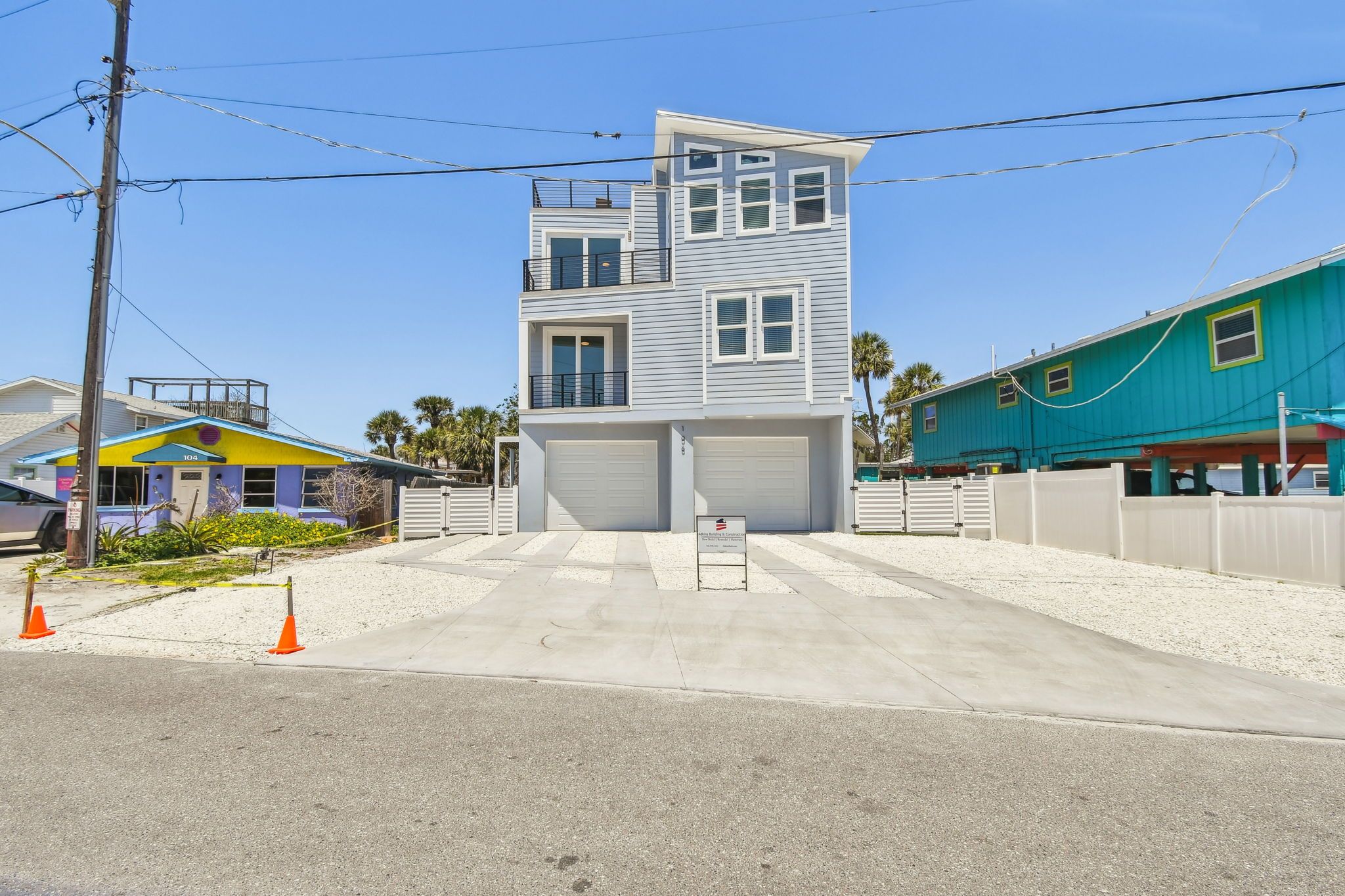 Three-story coastal home with a rooftop deck and two-car garage, seen from the street — Coastal custom home, Bradenton Beach