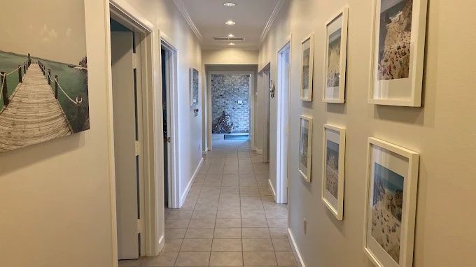 Tiled hallway lined with framed beach photographs, Bradenton Research Center