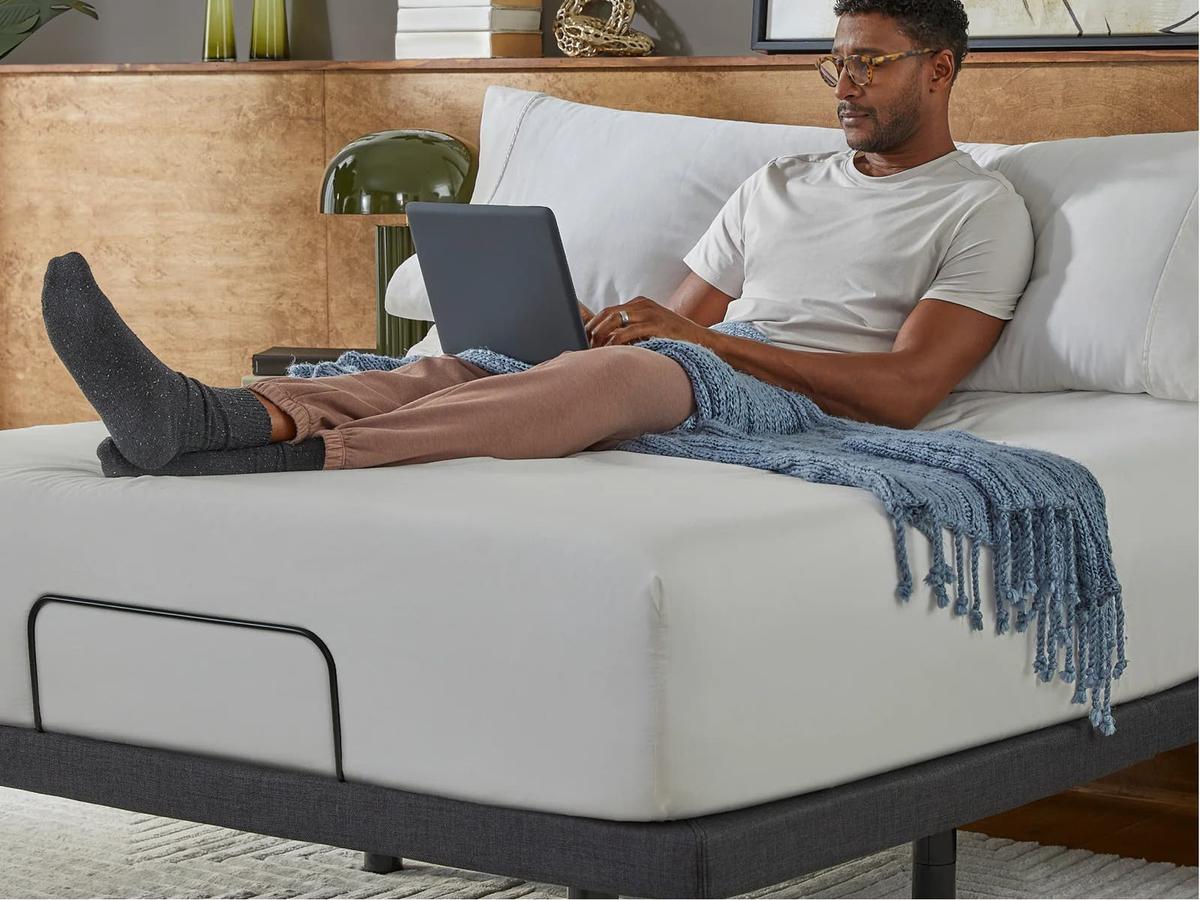 Man working on a laptop, sitting up in bed on the Platinum base
