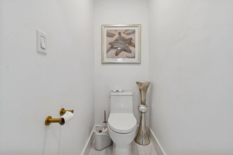Powder room white toilet gold hardware starfish art — New home construction, Longboat Key