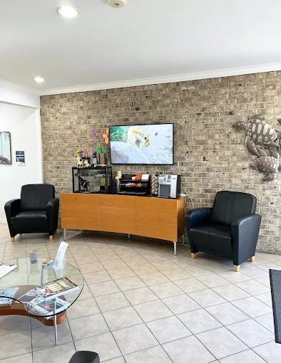 Lobby with a brick accent wall, TV console and black leather chairs, Bradenton Research Center