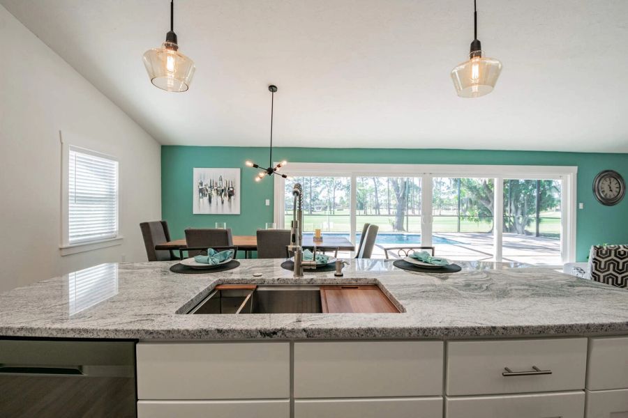 Kitchen island sink with teal dining wall — Custom home addition, pool, and renovation, Bradenton