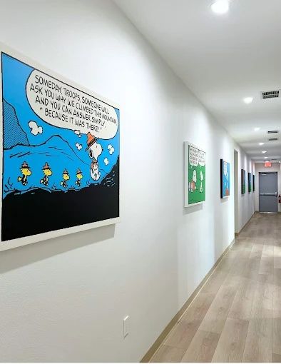 Corridor with wood-look plank flooring and framed comic-strip art, Bradenton Research Center