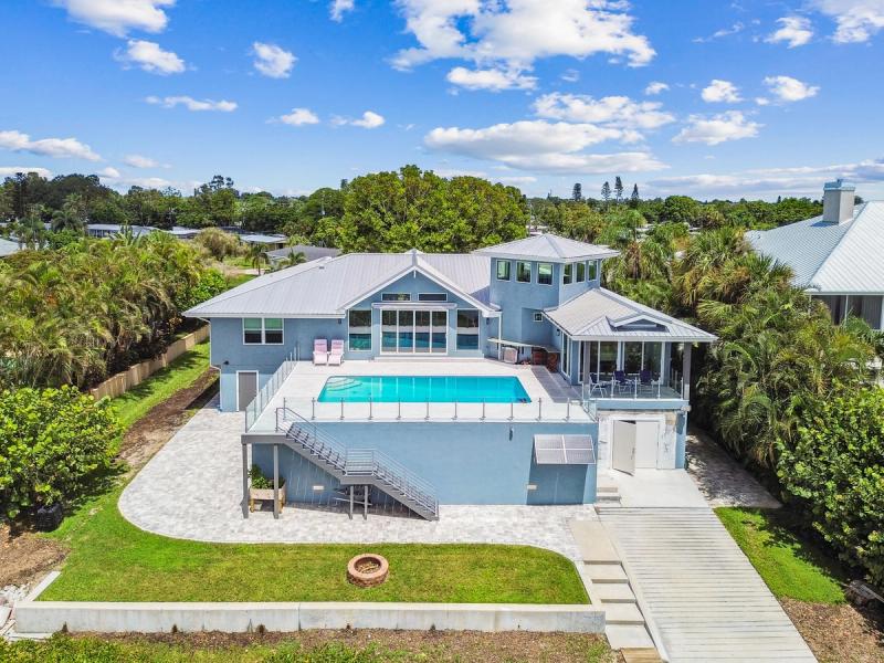 Drone view of the renovated waterfront home, elevated pool deck and lawn — Waterfront home renovation