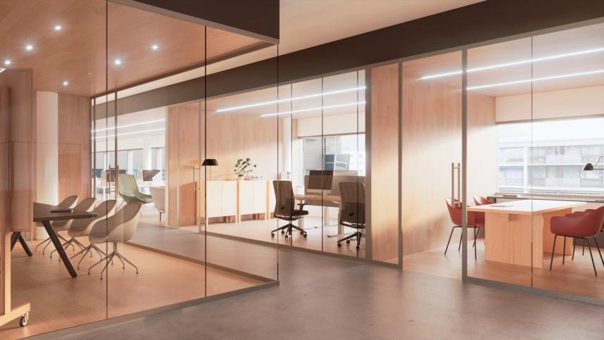 A photo of an office. We see office spaces from a bright hallway with glass walls and big windows.