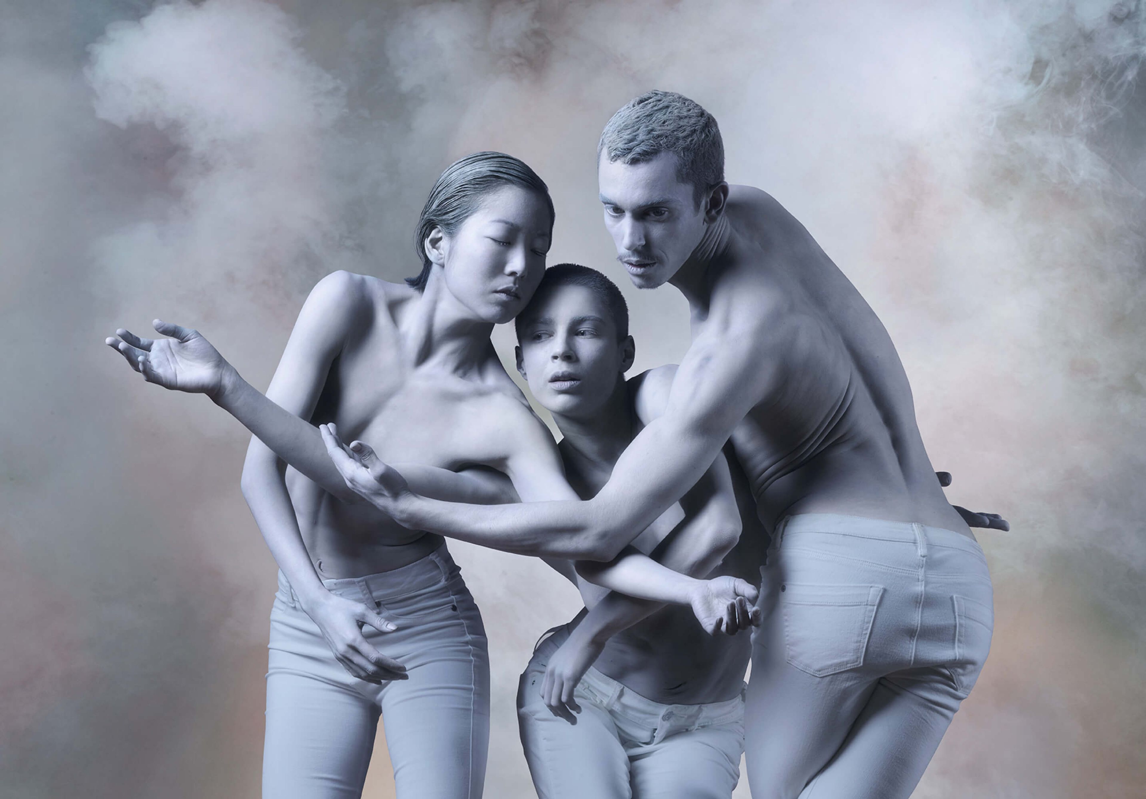 An illustrative photo from a show production, showing three people painted white, intertwined as if dancing.