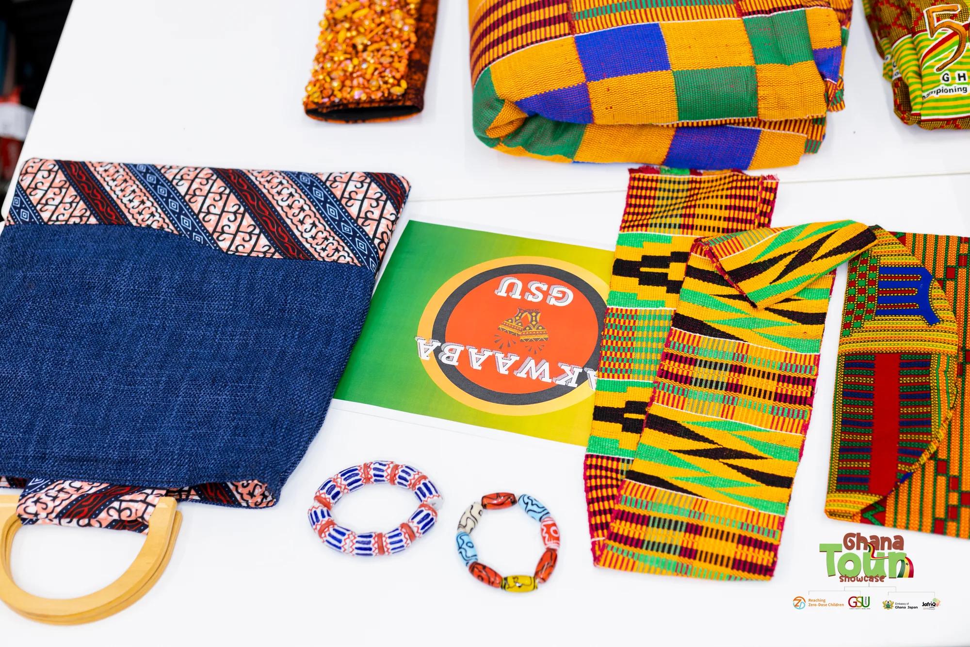 Kente cloth, beaded bracelets and woven crafts laid out on a display table