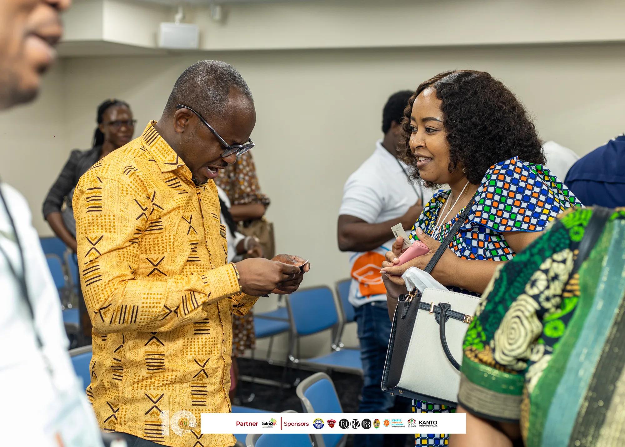 Guest in a kente shirt chats with an attendee during networking