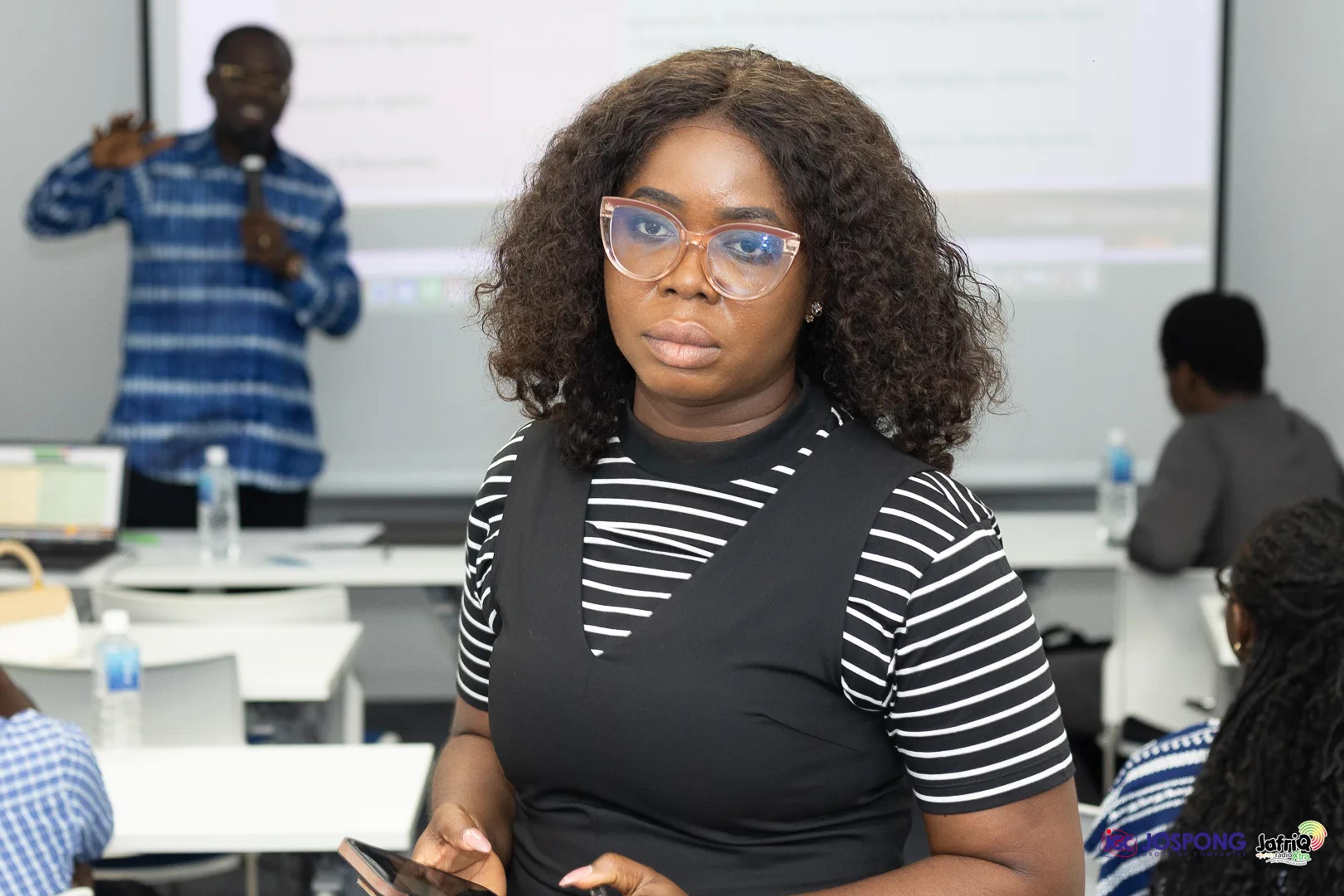 Student stands in seminar room as speaker presents slides behind her