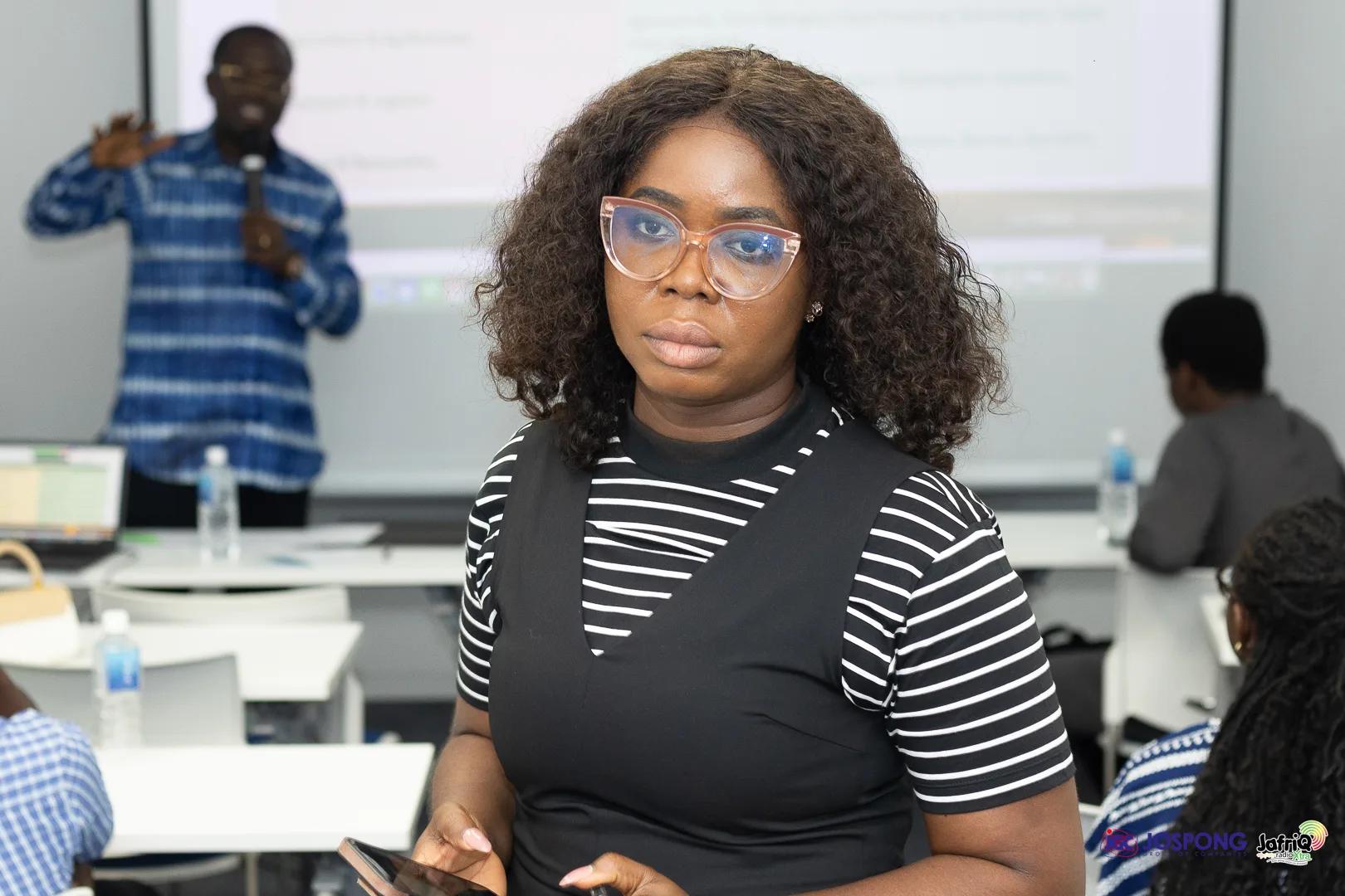 Student stands in seminar room as speaker presents slides behind her