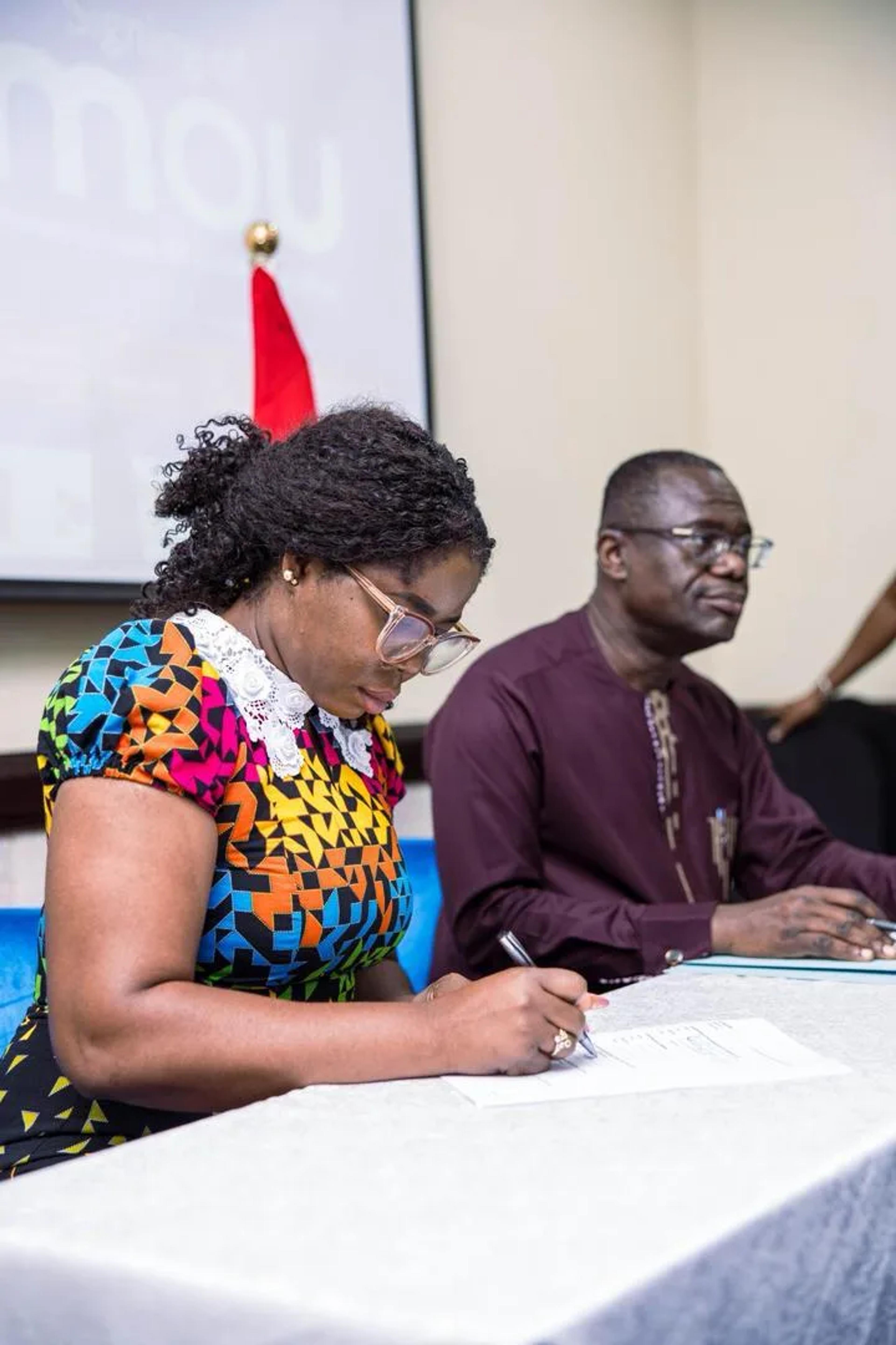 Caroline Awuye signing the memorandum of understanding