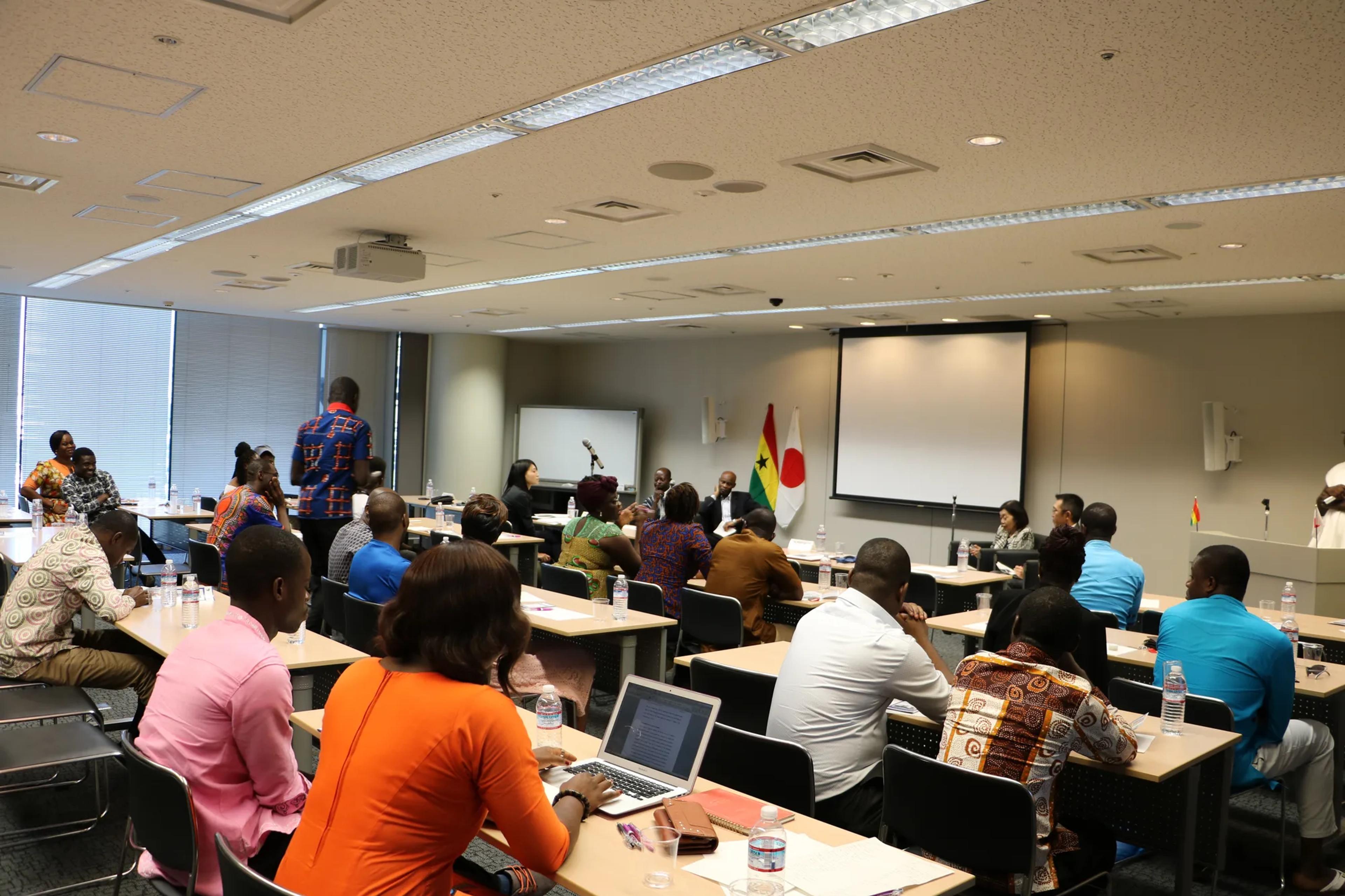 Students listening to the panel, with the flags of Ghana and Japan