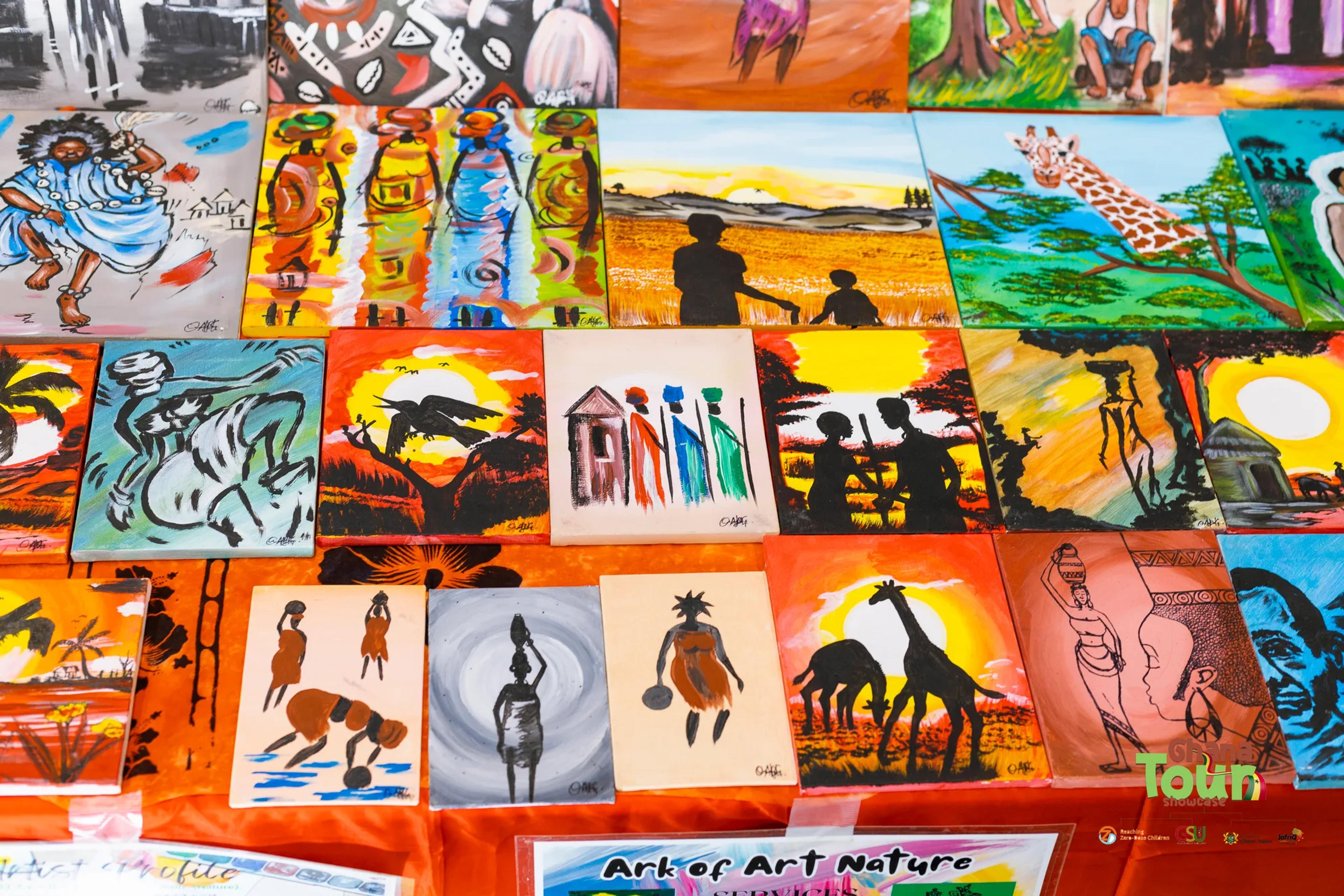 Table of vibrant Ghanaian paintings showing landscapes, wildlife and village life