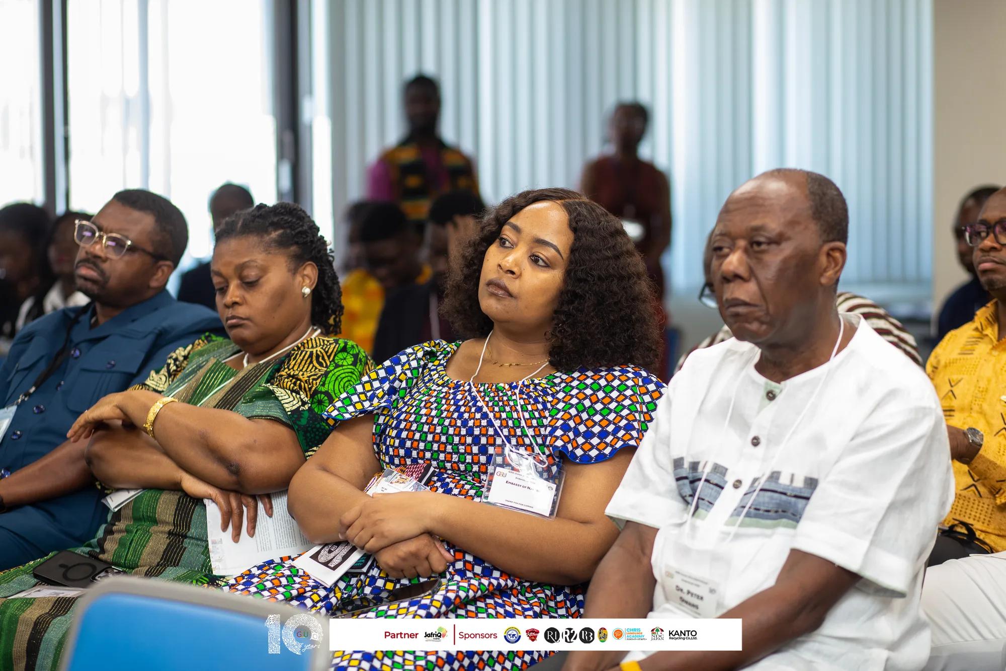 Attendees in Ghanaian prints listen attentively in the seminar room