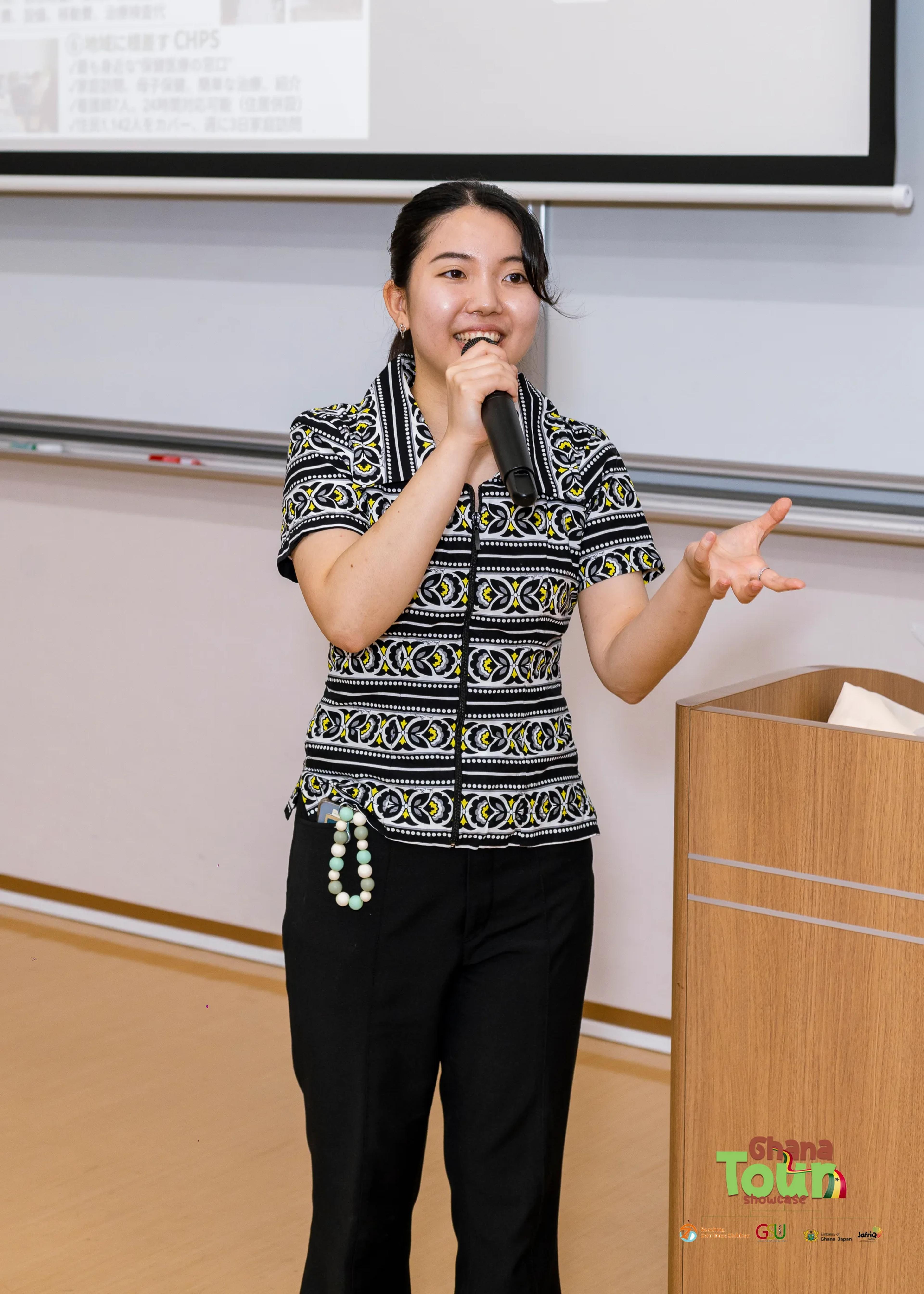 Host in patterned top speaks into a microphone to open the showcase
